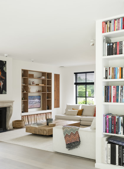 Leefruimte met inbouwkasten en boekenrek in woning in Herent